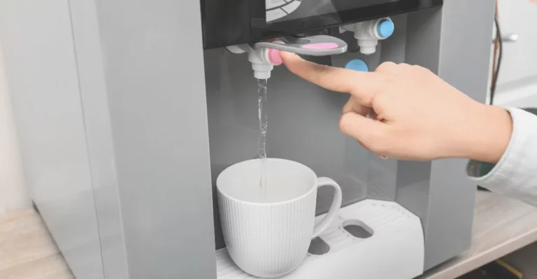 mão de uma pessoa enchendo um copo de água em um filtro de água